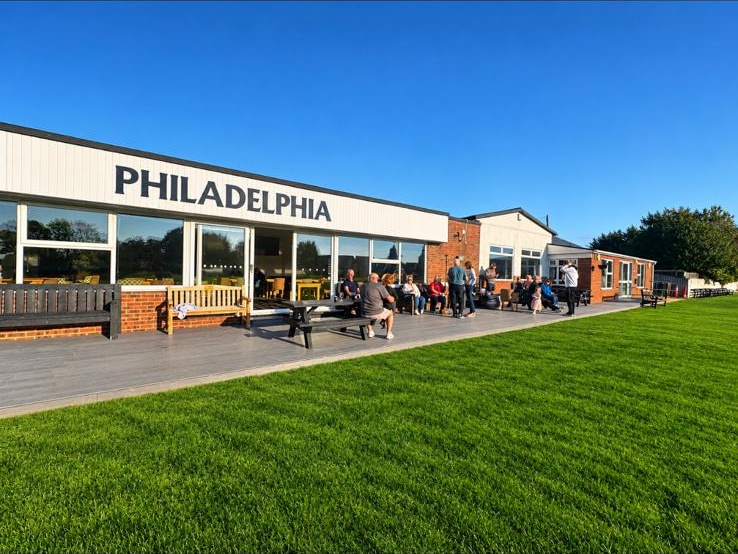 Philadelphia clubhouse and outdoor seating beside the cricket ground on a sunny day